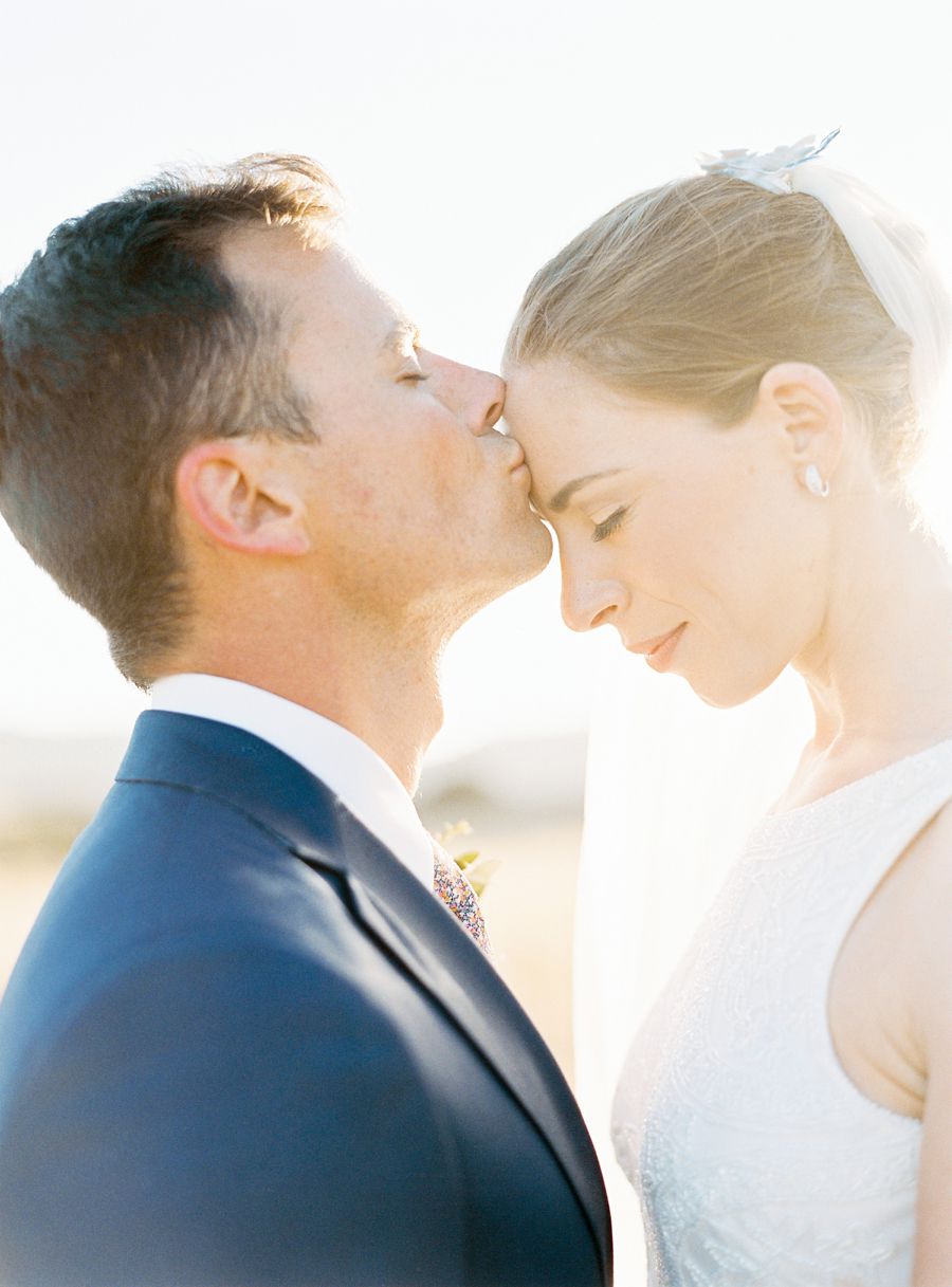 The groom kissing the brides forehead in the golden light in the sunset Photography: 2 Brides Photography - www.2brides.se