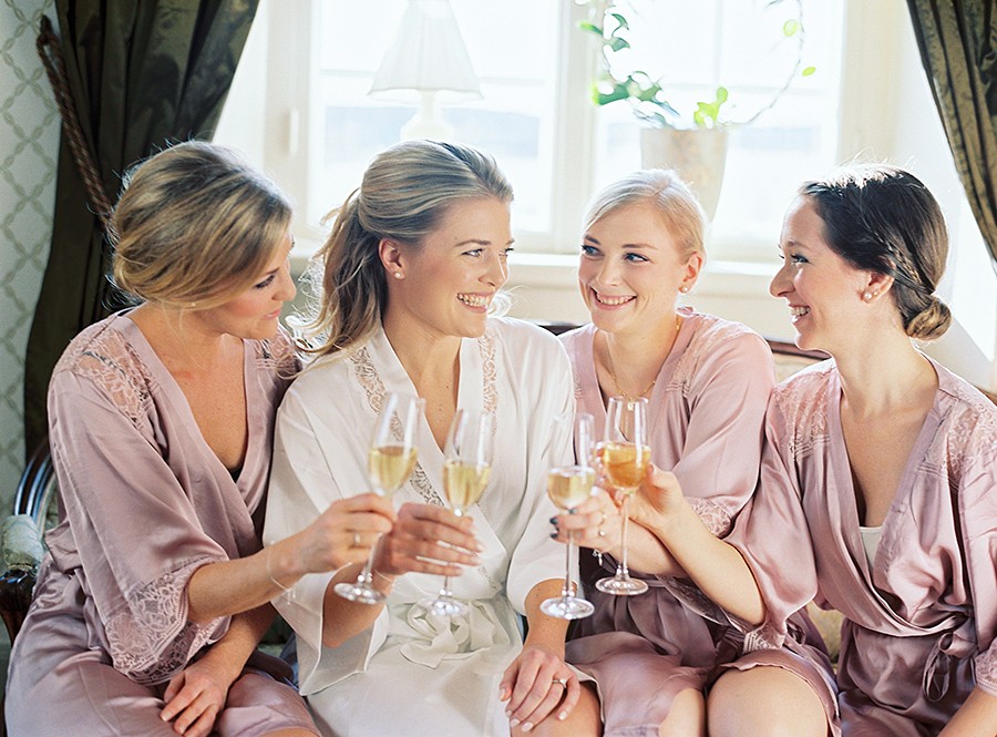 The bride with her bridesmaids having champagne dressed in cute pink silk robes 