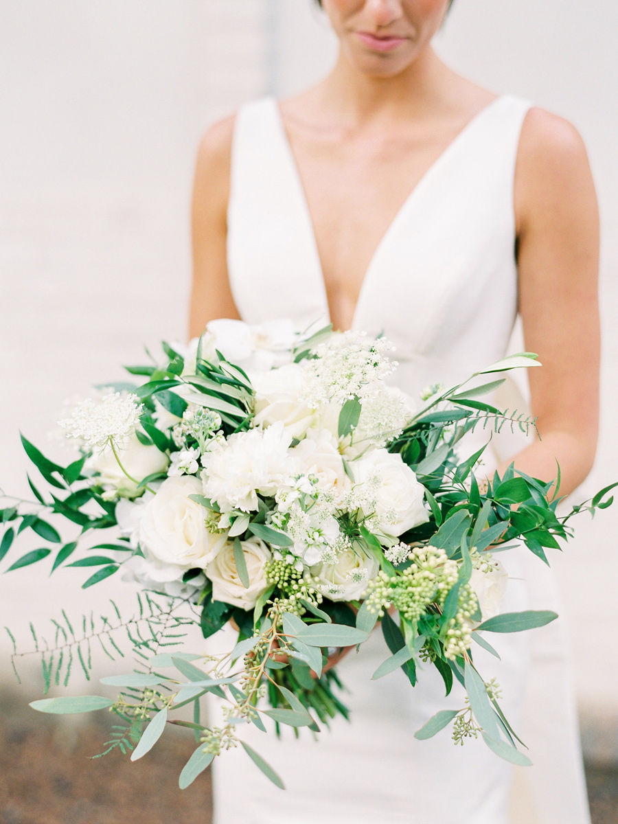 Asymmetric white wedding bouquet with touches of green foliage