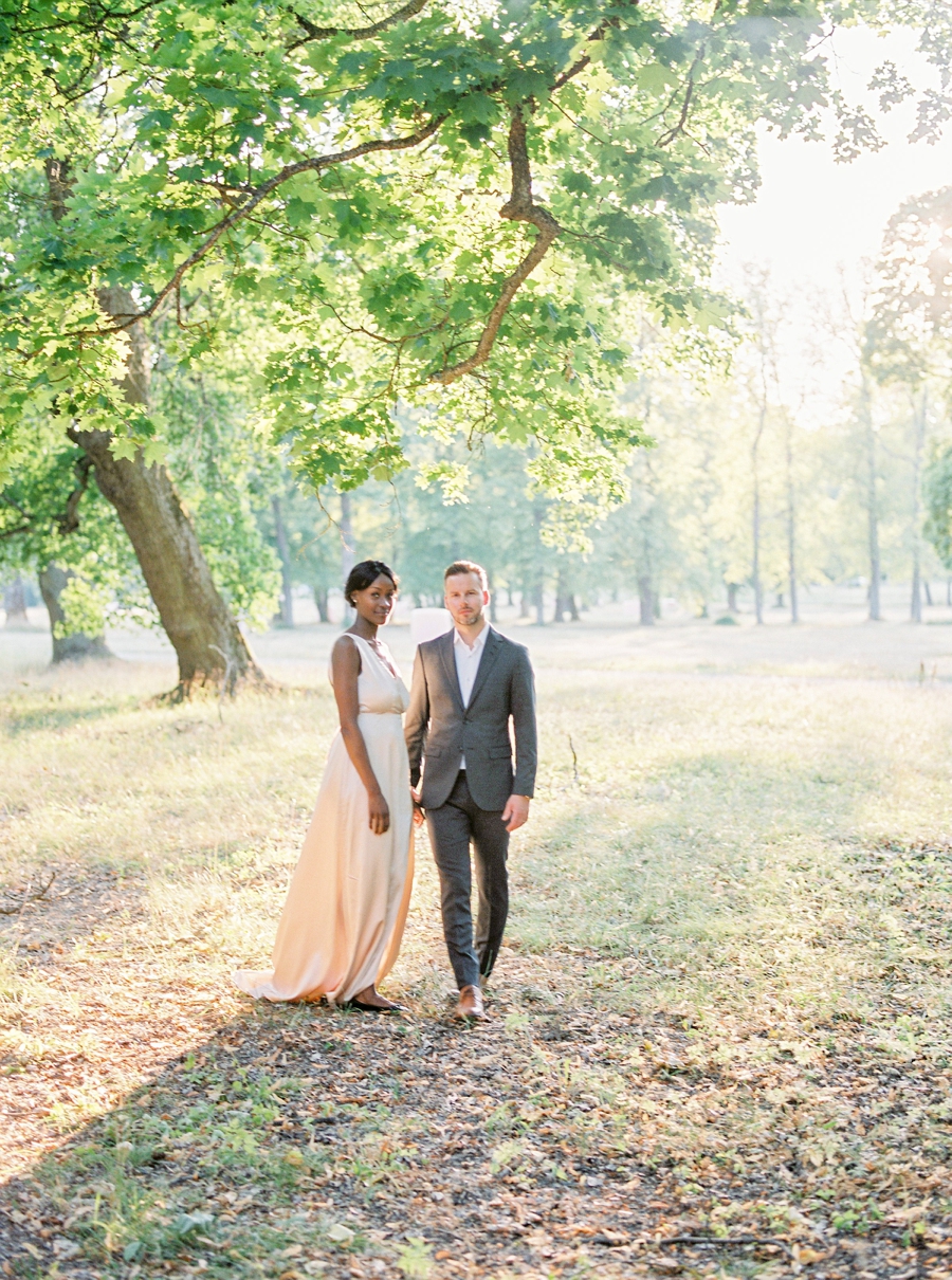 Wide shot of the couple in a light filled forest during golden hour. Photograph taken in Ekerö outside of Stockholm by 2 Brides Photography