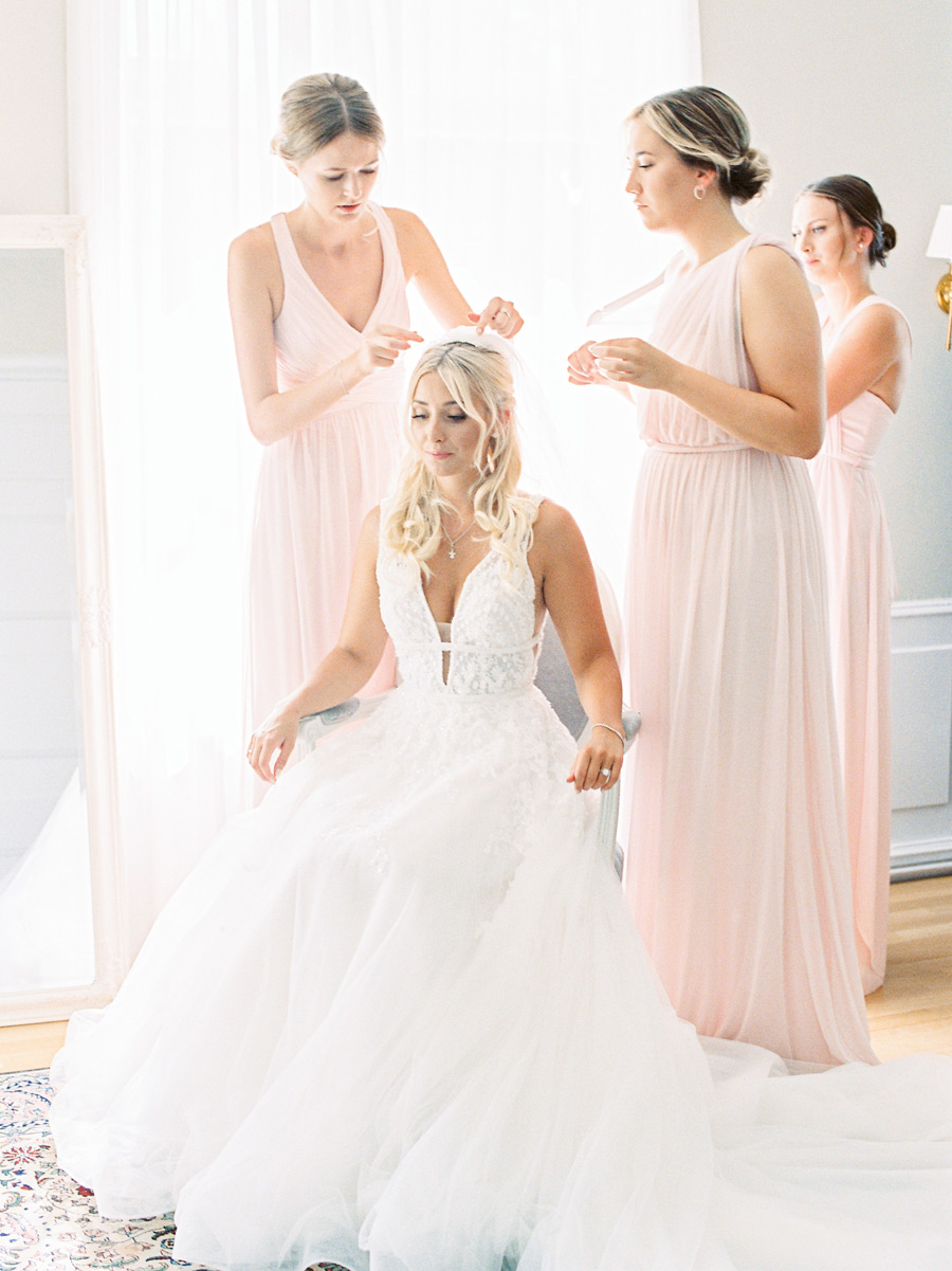 three bridesmaids helping the bride to put her veil on
