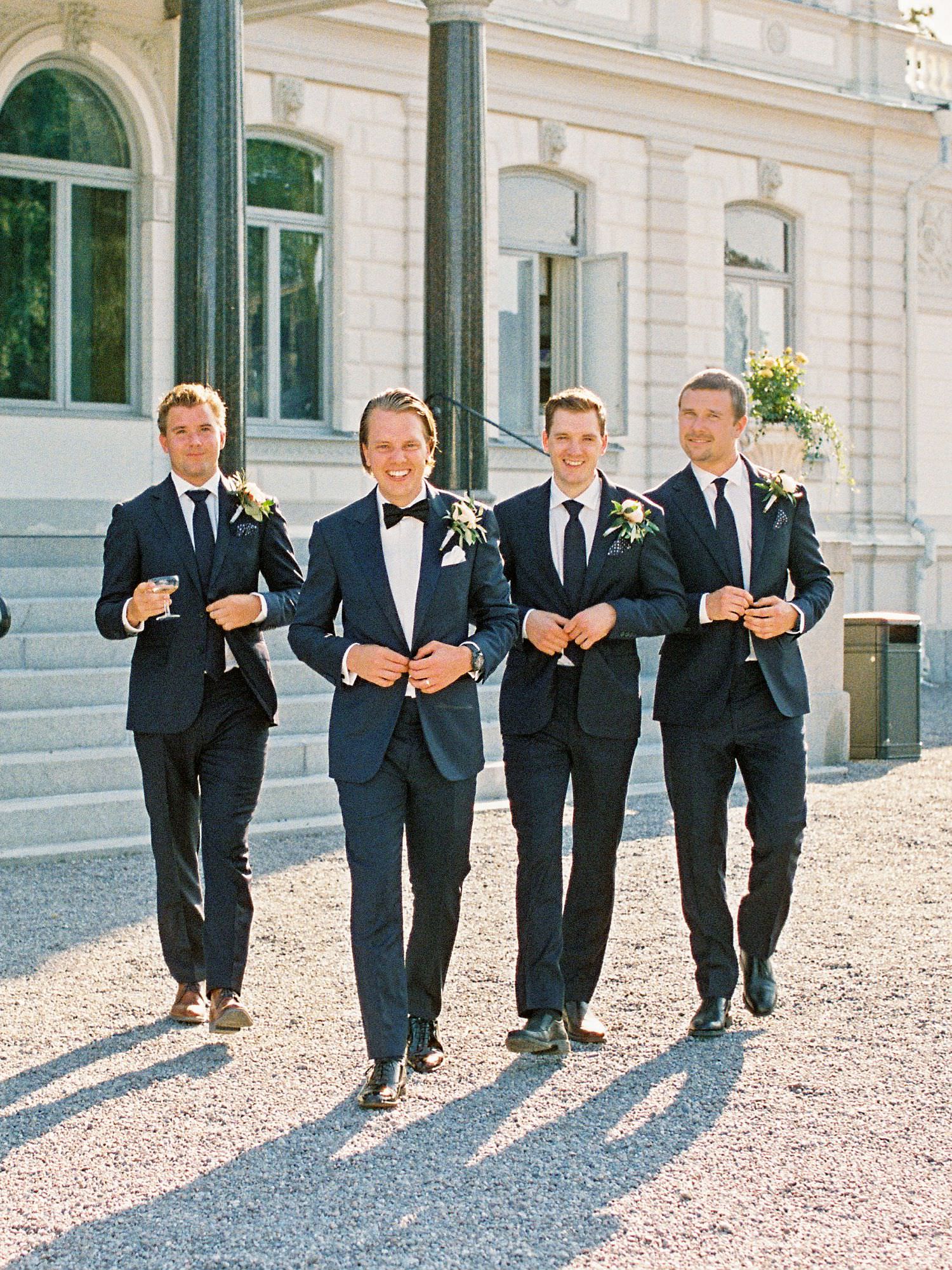 Groom and groomsmen walking away from the castle in the sunset