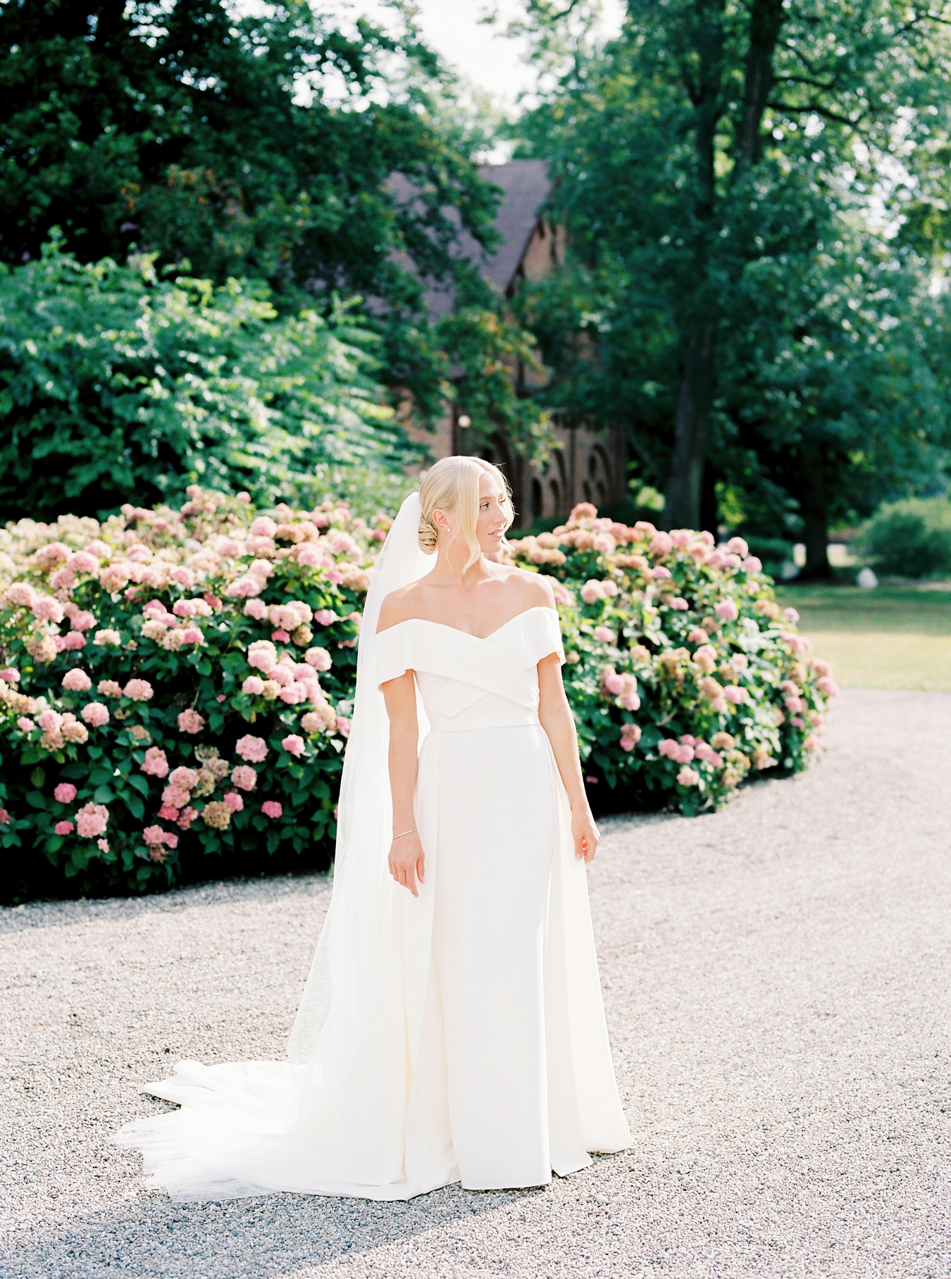 The bride standing infront of a large floral hedge with pink flowers at Jordberga Skåne