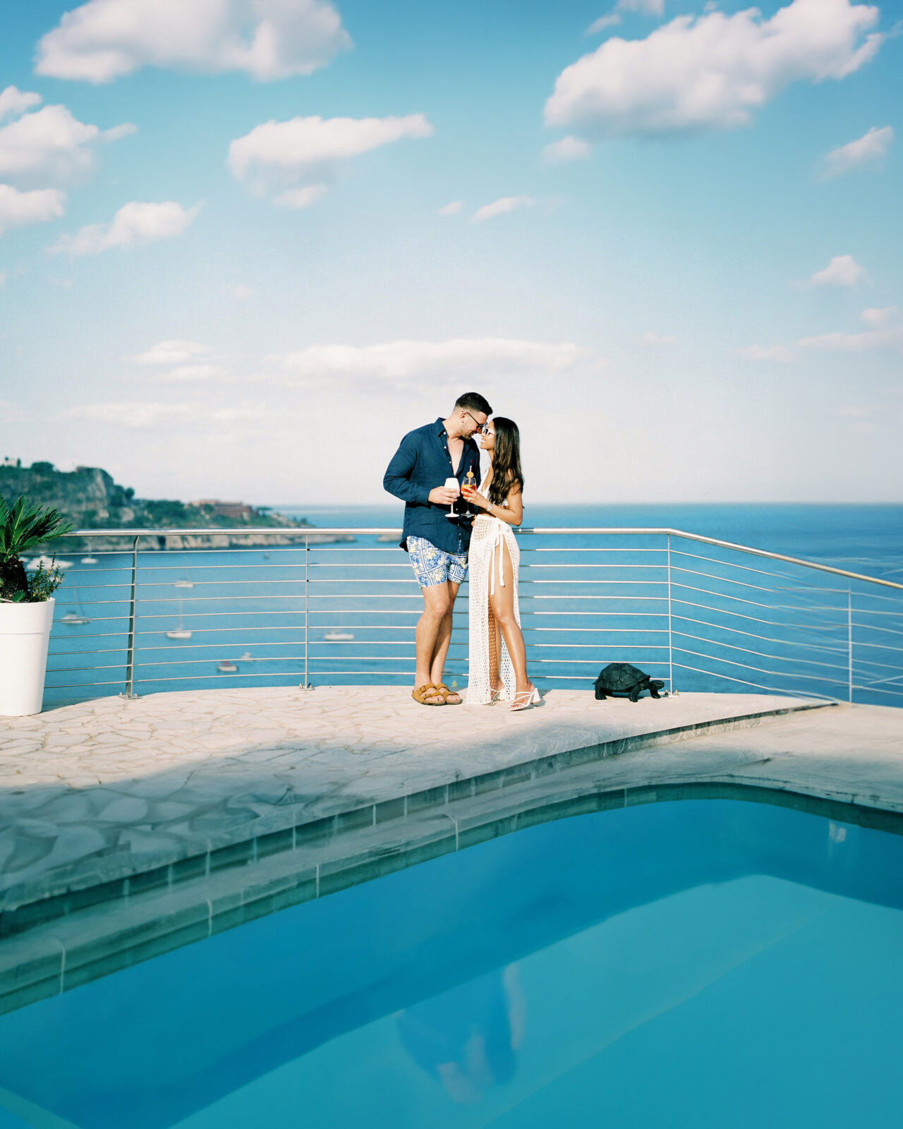 A couple sharing a kiss by a pool overlooking the sea at Baya Bella Luxury Villa in Taormina, Sicily.