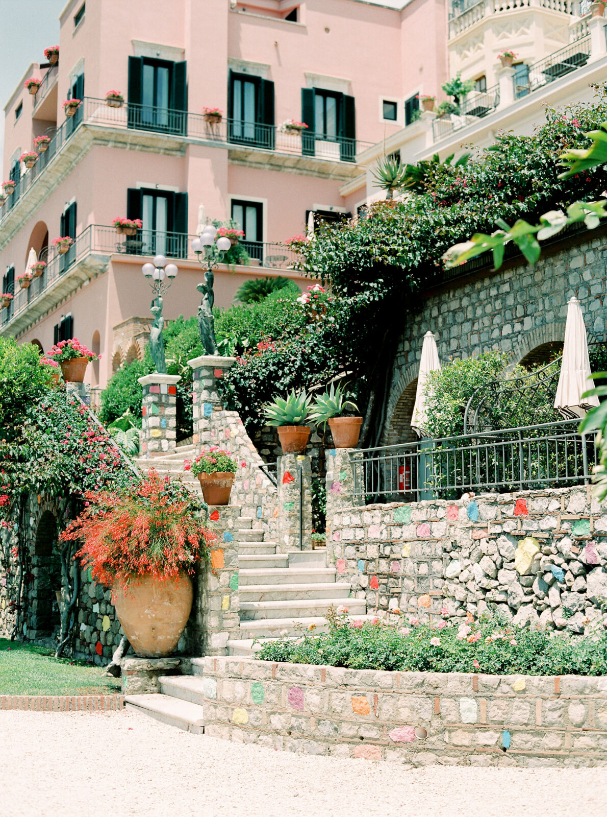 (direct upload) A colorful Mediterranean-style building adorned with a lush garden and stone steps.