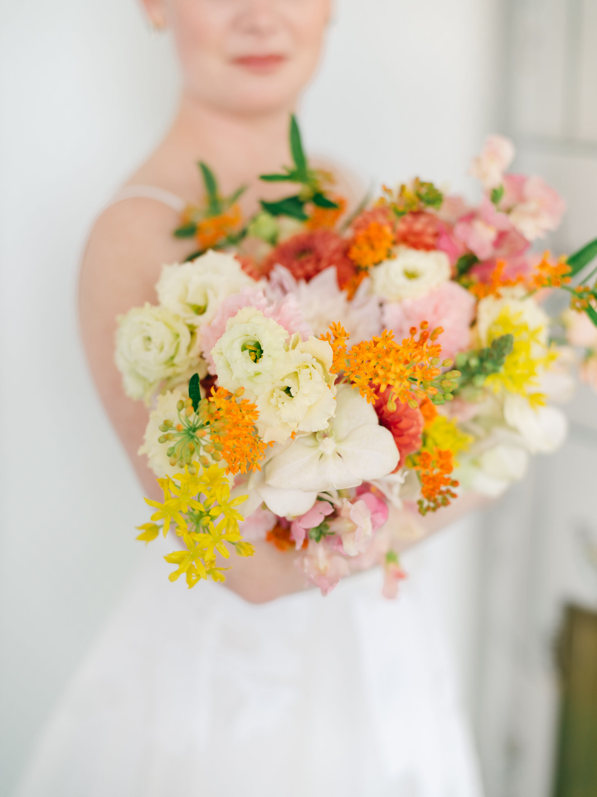 Bride holding a bright and colorful bouquet with citrus tones and unexpected florals